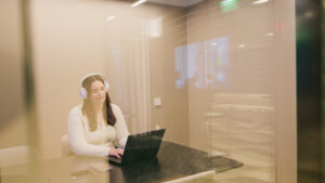 Palvelukoordinaattori tietokoneen äärellä kuulokkeet päässä vastaamassa Mainiokotien palvelunumeron puheluihin