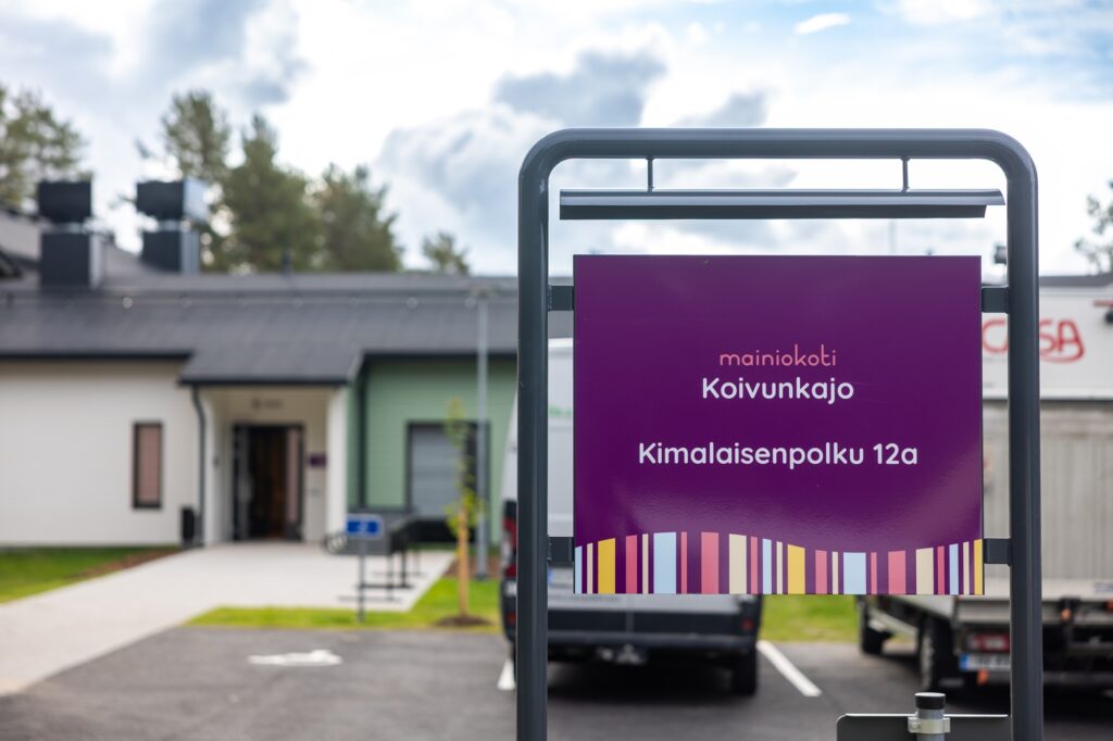 Mainiokoti Koivunkajon opaste sekä rakennuksen sisäänkäynti.