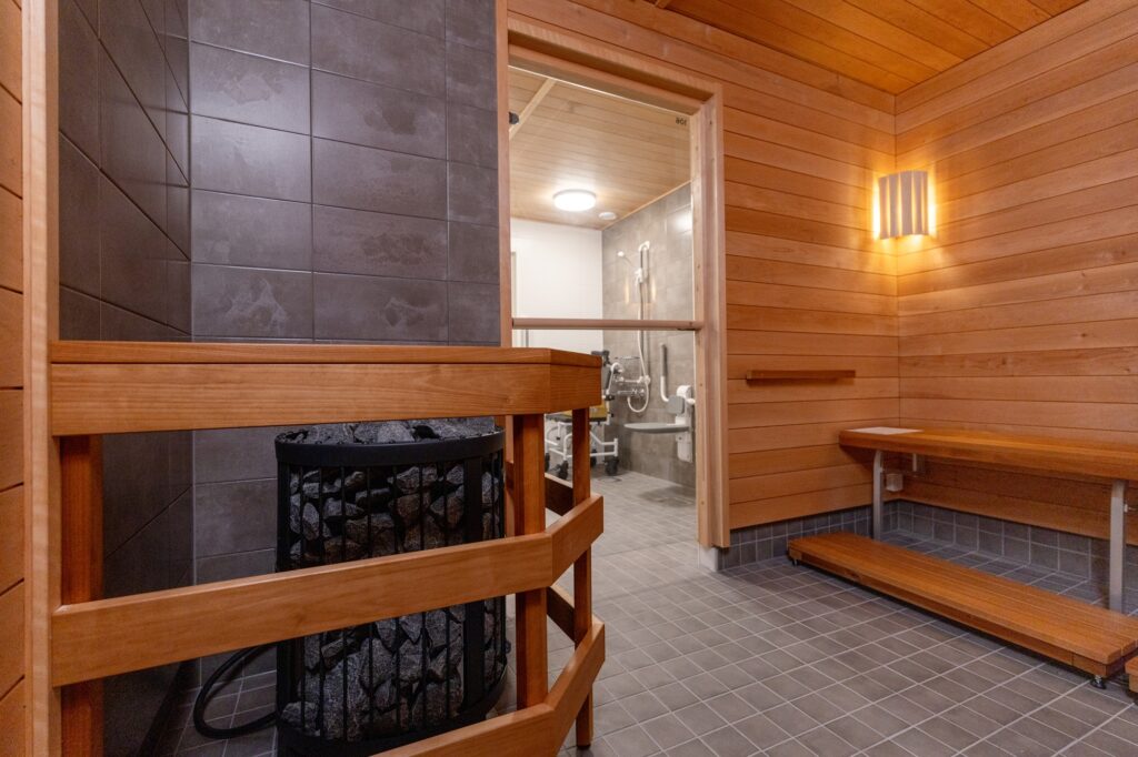 Sauna, jossa on puupenkit, kiuas ja yhteys pesutilaan.