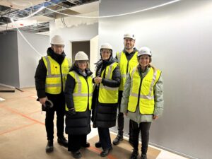 Mainiokotien johtoryhmä huiomioliiveissä ja suojakypärissä Munkkiniemen kohteen työmaalla