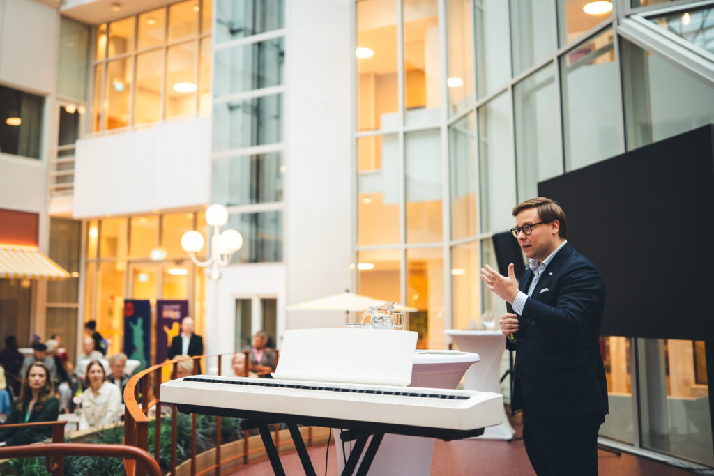 Helsingin pormestari pitämässä puhetta atrium-pihalla valkoisen pianon vieressä. 