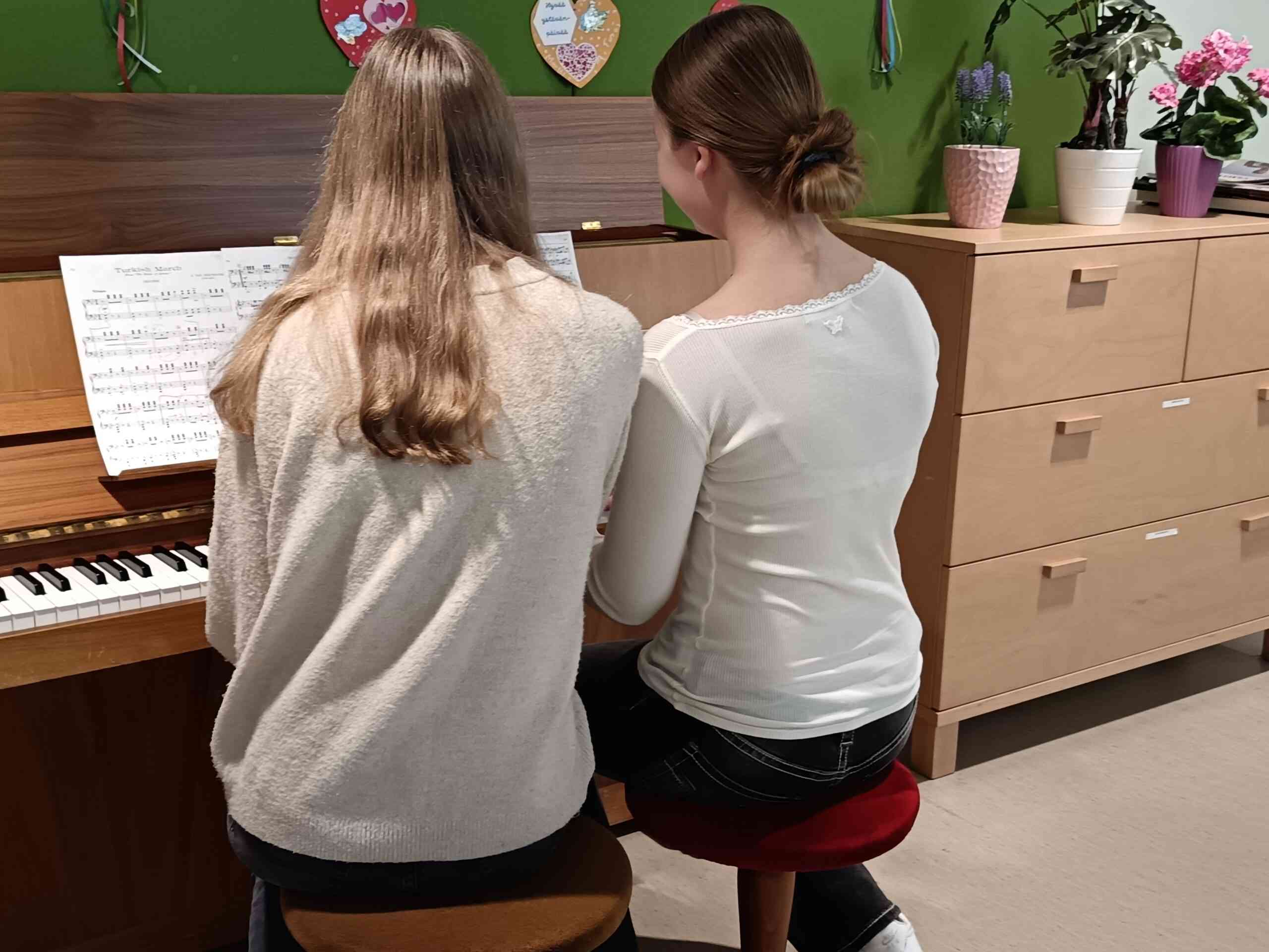 Kaksi henkilöä soittamassa pianoa